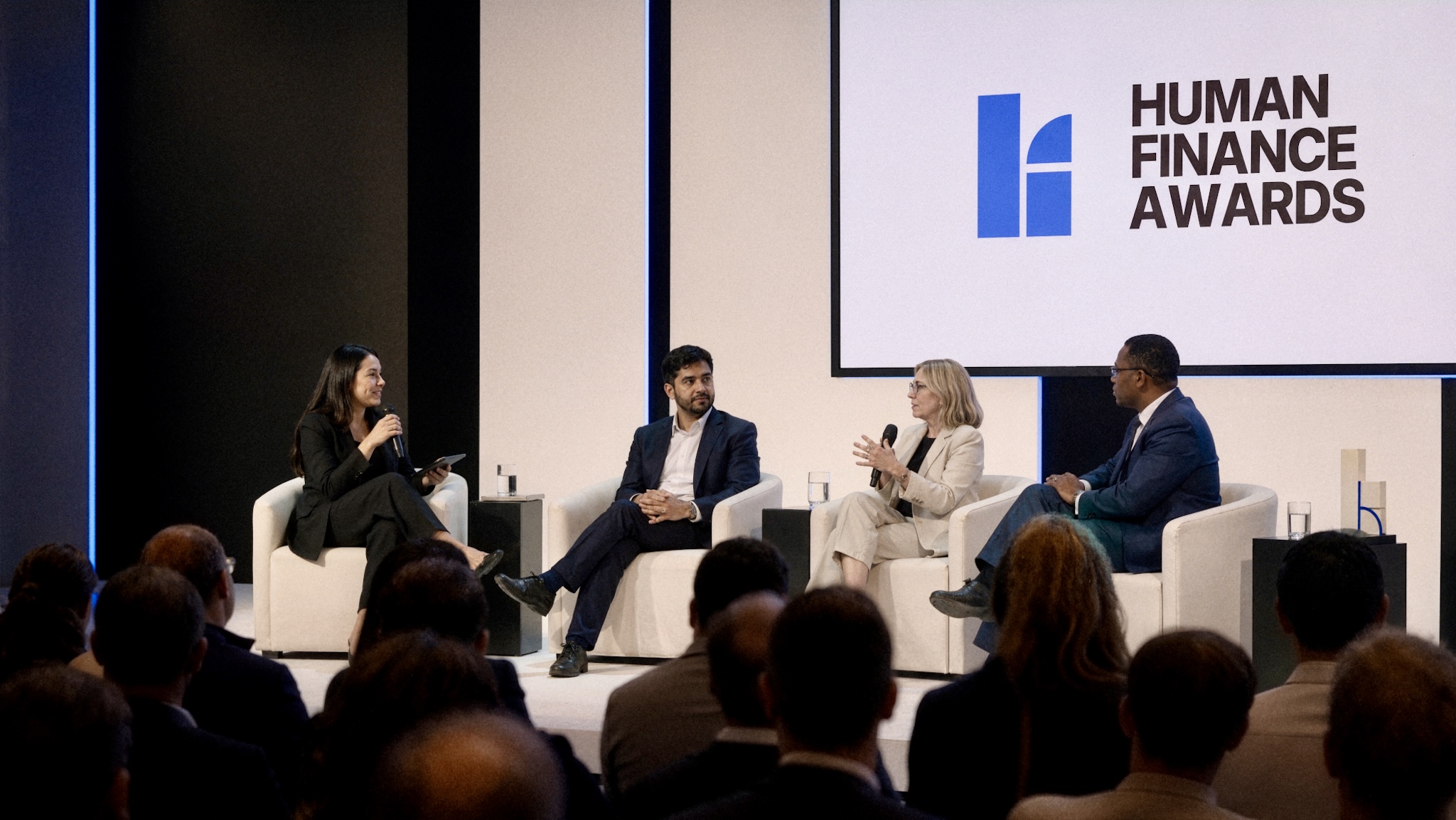 Four panelists seated onstage beneath the Human Finance Awards logo